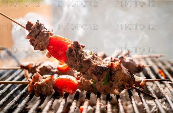 Grilled meat skewers. Close up of homemade roast beef on the grill, Roast beef skewer with tomato. Details of a delicious homemade roast beef