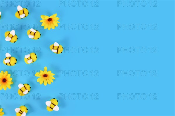 Cute felt bees and yellow flowers on side of blue background with copy space