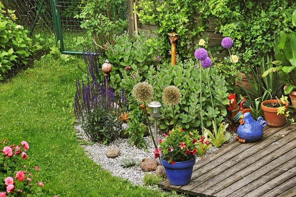 Garden corner with flowers and clay figures, Munich, Bavaria, Germany, Europe