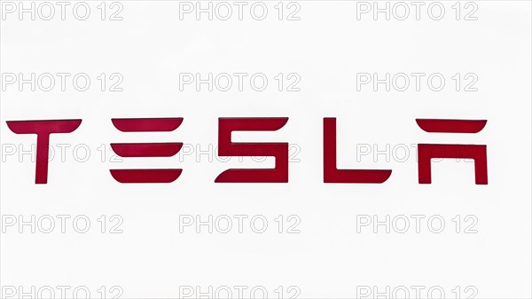 Red Tesla lettering on white background, company logo on a Supercharger, Sweden, Europe