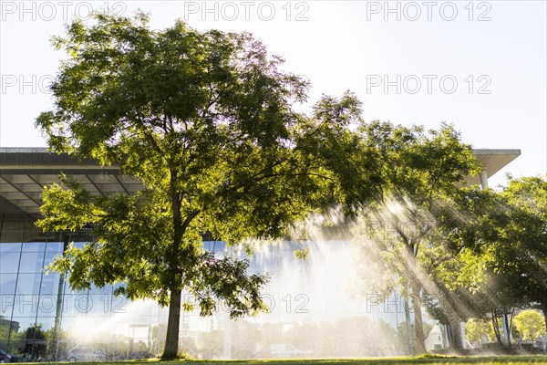 A meadow and a tree are watered in front of the Paul-Loebe-Haus in the government quarter Berlin, 22.06.2022., Berlin, Germany, Europe