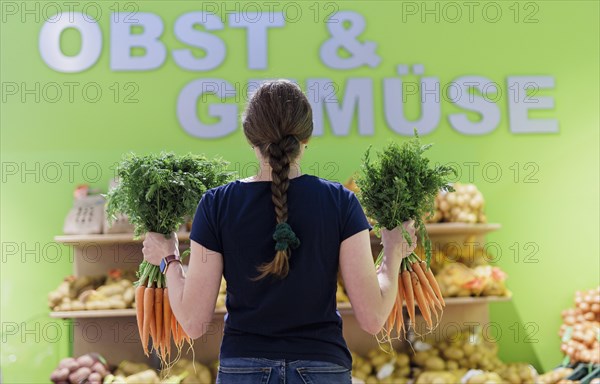 Woman buying carrots at the supermarket, Radevormwald, Germany, Europe