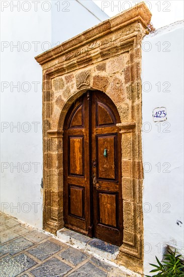 Old wooden doors with pebble mosaics on the floor, winding streets with white houses, Lindos, Rhodes, Greece, Europe