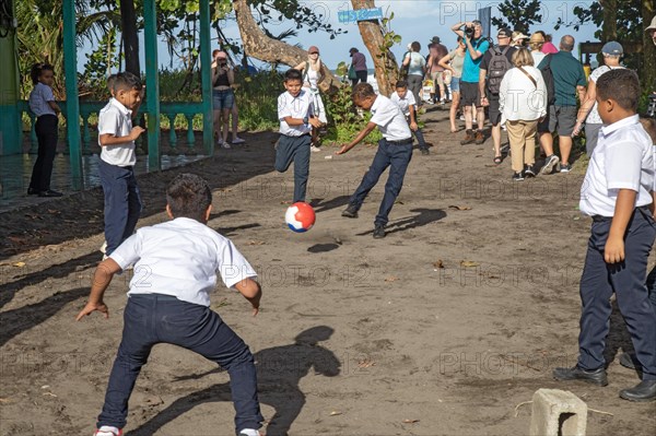 Tortuguero, Costa Rica, As tourists walk by, school boys play football