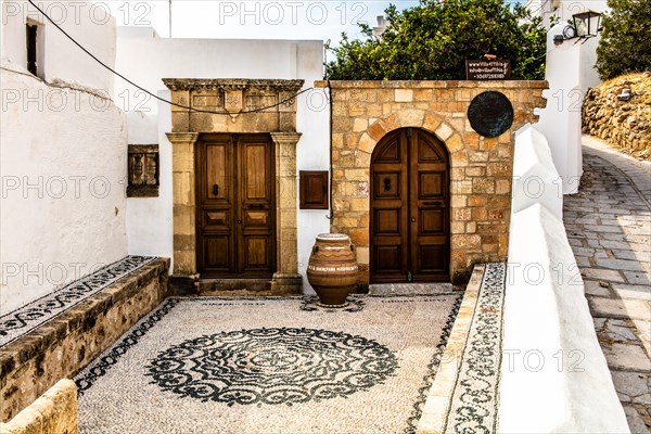 Old wooden doors with pebble mosaics on the floor, winding streets with white houses, Lindos, Rhodes, Greece, Europe