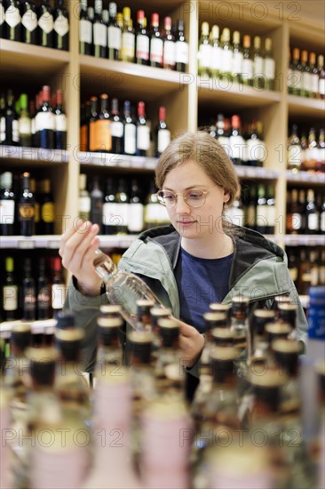 Young woman, student buys alcoholic drinks at the supermarket. Radevormwald, Germany, Europe