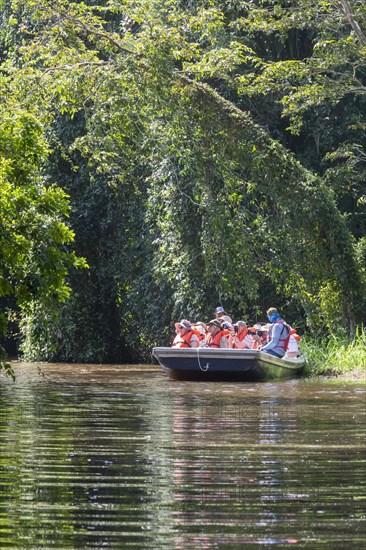 Tortuguero National Park, Costa Rica, Tourists ride a boat on a wildlife viewing excursion on Cano Palma river, Central America