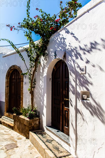 Old wooden doors with pebble mosaics on the floor, winding streets with white houses, Lindos, Rhodes, Greece, Europe