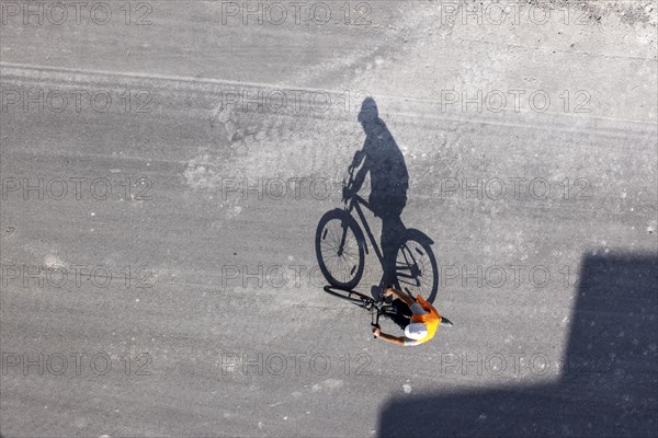 Construction worker with safety helmet driving on a road, he casts a long shadow, Stuttgart main station, Baden-Wuerttemberg, Germany, Europe