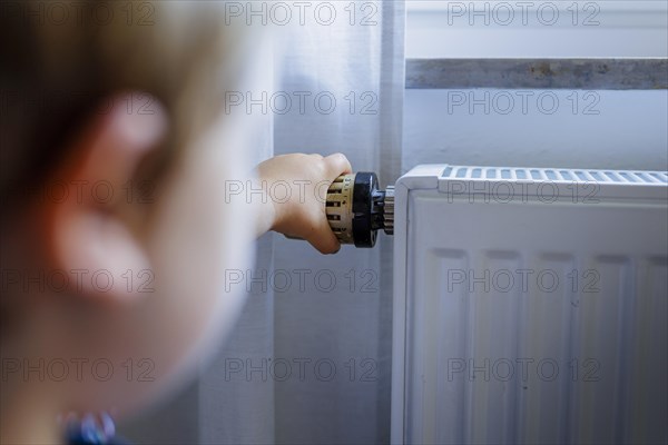 Bonn. Toddler turns the heating thermostat. Bonn, Germany, Europe