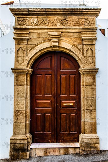 Old wooden doors with pebble mosaics on the floor, winding streets with white houses, Lindos, Rhodes, Greece, Europe