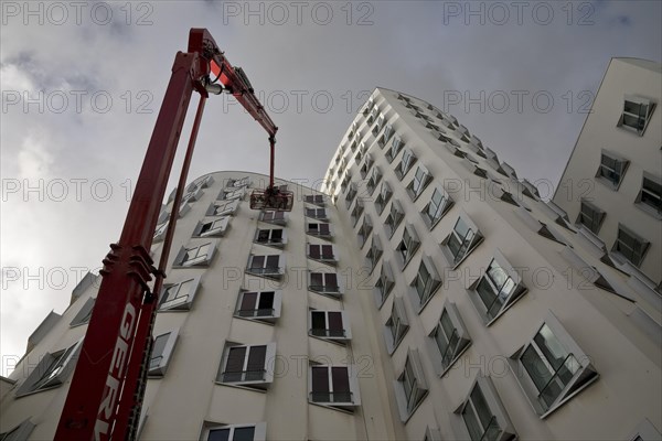 Building cleaner on a working platform with extended crane at Gehry Bau Neue Zollhof 3, Duesseldorf, North Rhine-Westphalia, Germany, Europe