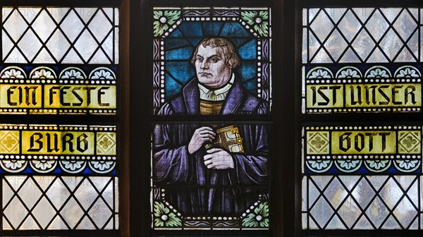 Portrait of Luther as a stained glass window with the words Eine feste Burg ist unser Gott, Evangelische Jakobuskirche, Breckerfeld, North Rhine-Westphalia, Germany, Europe