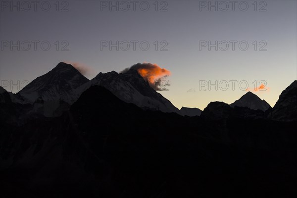 Daybreak at Gokyo Ri. Three clouds mark three eight-thousanders, Mount Everest on the left, Lhotse in the middle and Makalu on the right-hand-side in the greater distance. Silhouette of the mountain ridges. Gokyo Trek, Khumbu, the Everest Region, Himalayas. Sagarmatha National Park, a UNESCO World Heritage Site. Solukhumbu, Nepal, Asia