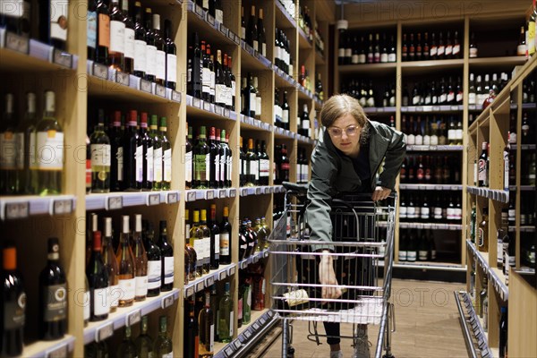 Young woman buys alcoholic drinks in supermarket. Radevormwald, Germany, Europe