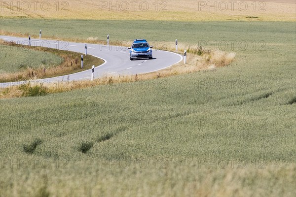 A police patrol car driving on a country road in Pfaffendo, Pfaffendorf, Germany, Europe