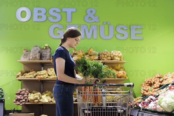 Woman buying carrots at the supermarket, Radevormwald, Germany, Europe