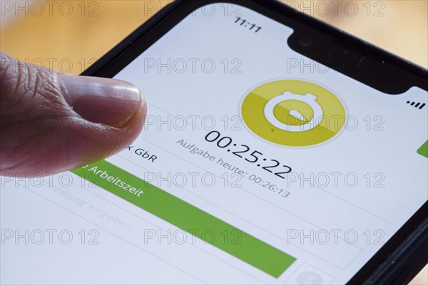 Symbolic photo on the subject of digital time recording. The Clockodo app is used to record an employees working hours on a smartphone. Berlin, Berlin, Germany, Europe