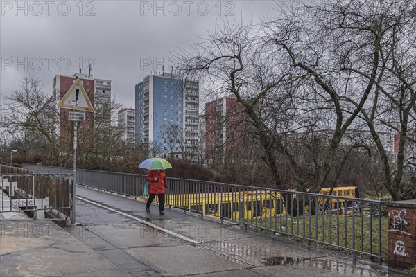 A woman with a colourful umbrella stands out in front of a block of flats in the district of Marzahn, photographed in Berlin, 01.02.2023., Berlin, Germany, Europe