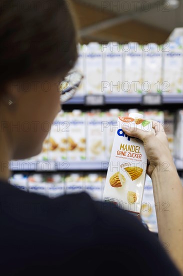 Younger woman buys almond milk without sugar in the supermarket. Radevormwald, Germany, Europe