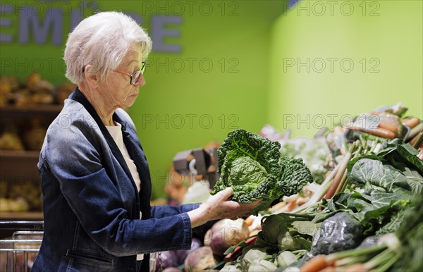 Elderly woman buys a savoy cabbage in the supermarket, Radevormwald, Germany, Europe