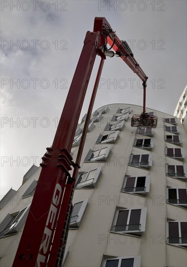 Building cleaner on a working platform with extended crane at Gehry Bau Neue Zollhof 3, Duesseldorf, North Rhine-Westphalia, Germany, Europe