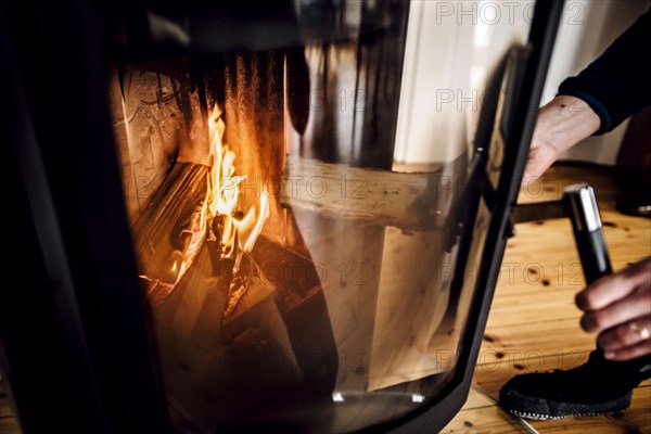 Symbolic photo: A woman throws a log into a fireplace. Berlin, 03.03.2023, Berlin, Germany, Europe