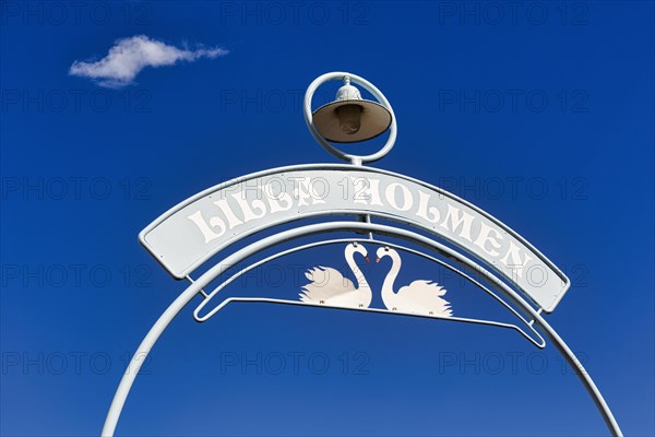 Sign with two swans and inscription Lilla Holmen against blue sky, entrance to park with beach, Mariehamn, Aland, Aland Islands, Alandinseln, Finland, Europe