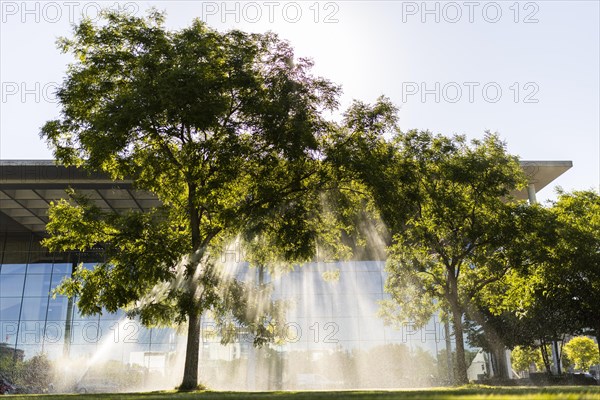 A meadow and a tree are watered in front of the Paul-Loebe-Haus in the government quarter Berlin, 22.06.2022., Berlin, Germany, Europe