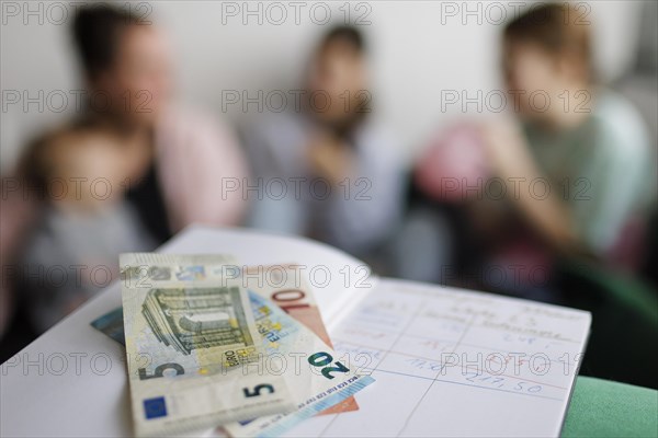 Household book with thirty-five euros. In the background a mother with three children., Bonn, Germany, Europe