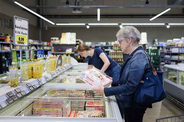 Elderly woman shopping in supermarket. Radevormwald, Germany, Europe