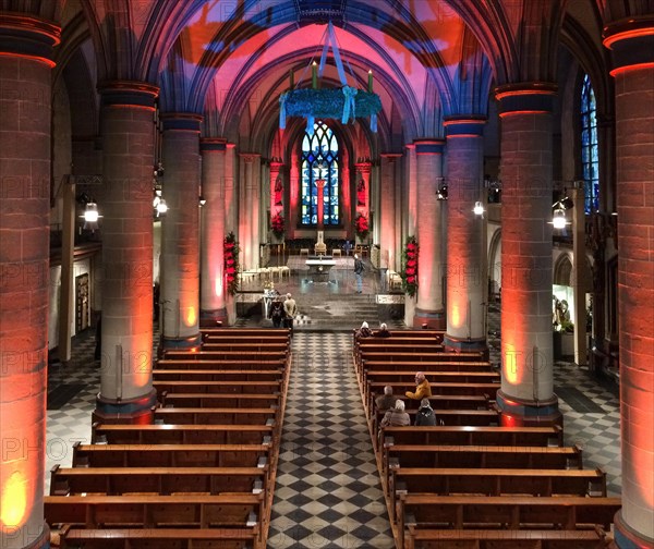 View from elevated position on festively lit interior central nave of Essen Cathedral Muenster former collegiate church cathedral church bishop's seat Ruhrbistum diocese Essen, Advent wreath hanging from ceiling above, Essen, North Rhine-Westphalia, Germany, Europe