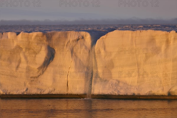 Brasvellbreen coastal glacier, glacier front with waterfall of melting ice, evening light at sunset, Nordaustlandet, Svalbard