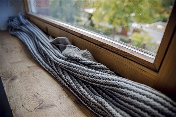 Symbolic photo on the subject of a cold flat. A blanket lies on the windowsill in front of a poorly insulated window to protect against cold air. Berl Berlin, Germany, Europe