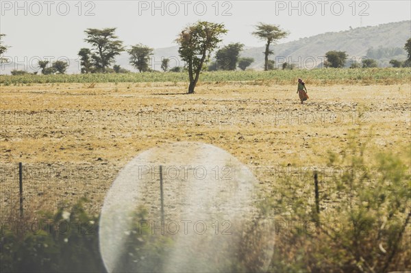 A woman walks across an arid field, photographed in Addis Ababa, 12.01.2023., Addis Ababa, Ethiopia, Africa