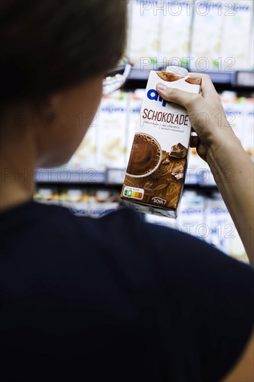 Younger woman buys a chocolate drink in the supermarket. Radevormwald, Germany, Europe