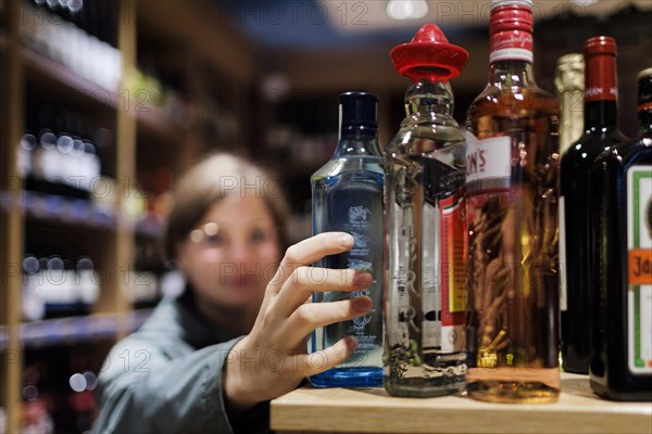 Young woman, student buys alcoholic drinks at the supermarket. Radevormwald, Germany, Europe