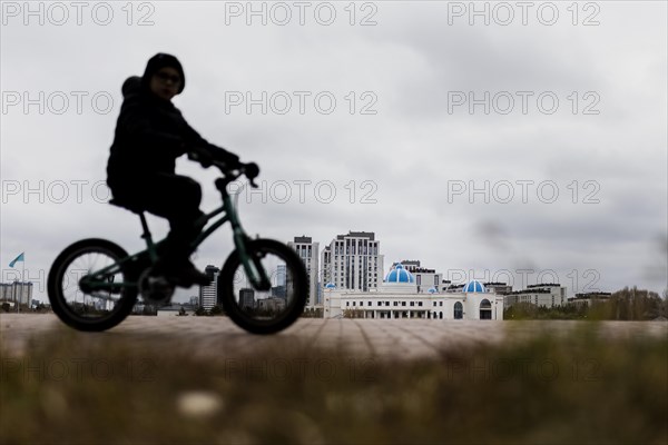 A child on a bicycle stands out in Astana, Astana, Kazakhstan, Asia