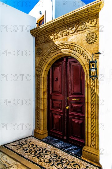 Old wooden doors with pebble mosaics on the floor, winding streets with white houses, Lindos, Rhodes, Greece, Europe