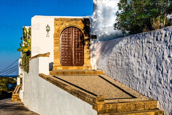 Old wooden doors with pebble mosaics on the floor, winding streets with white houses, Lindos, Rhodes, Greece, Europe