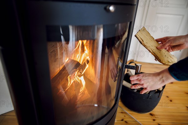 Symbolic photo: A woman throws a log into a fireplace. Berlin, 03.03.2023, Berlin, Germany, Europe