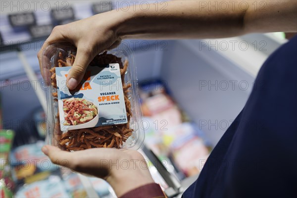 Young woman buys vegan bacon at the supermarket. Radevormwald, Germany, Europe