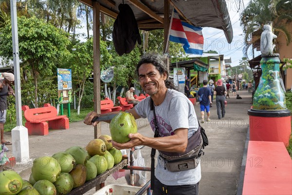 Tortuguero, Costa Rica, A street vendor cuts open a green coconut for a tourist in this small village on the Caribbean coast. The refreshing coconut water inside this then sipped through a straw, Central America
