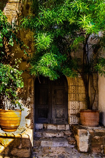 Old wooden doors with pebble mosaics on the floor, winding streets with white houses, Lindos, Rhodes, Greece, Europe