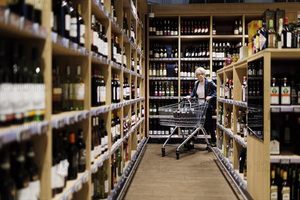 Elderly woman in the wine and spirits department of a supermarket in Radevormwald, 08.06.2022. Radevormwald, Germany, Europe