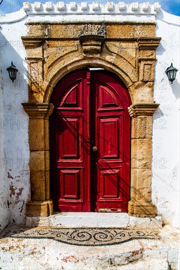 Old wooden doors with pebble mosaics on the floor, winding streets with white houses, Lindos, Rhodes, Greece, Europe