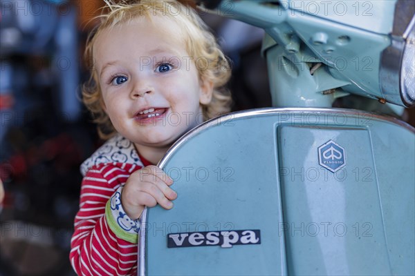 Little boy playing with a Vespa. Bonn, Germany, Europe