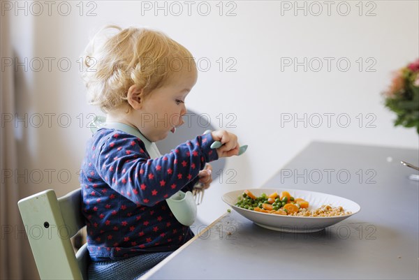 Bonn. Toddler eats a meal of peas, carrots and cereals. Bonn, Germany, Europe