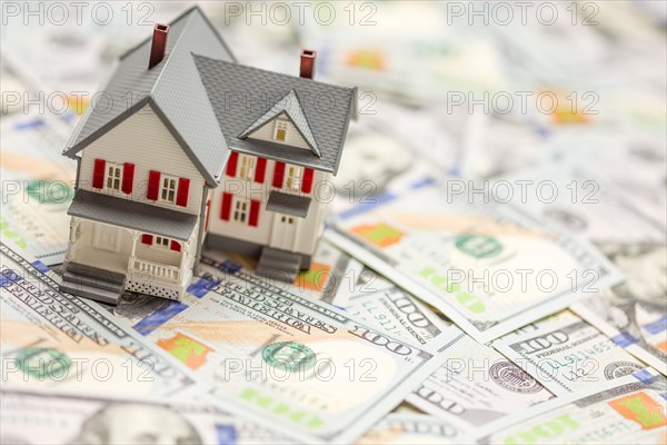 Small model house on layer of one hundred dollar bills