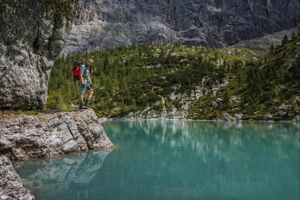 Tourist posing for a photo against the background of the beautiful Lago di Sorapis lake in the Italian Dolomites